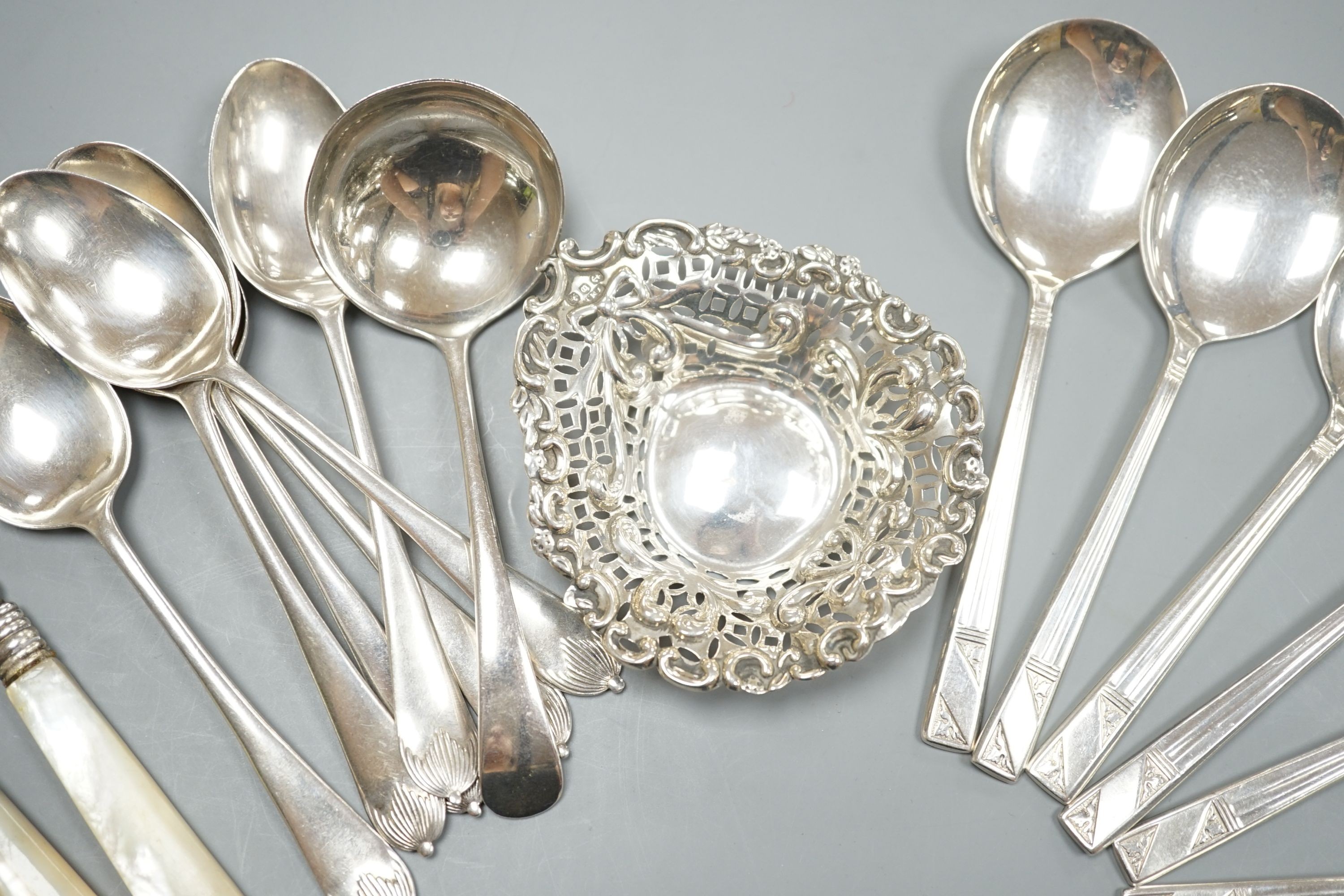 A late Victorian repousse silver bonbon dish, 91mm an assorted silver cutlery including three Victorian mother of pearl handled butter knives, a sauce ladle and two sets of six spoons including soup, weighable silver 11.